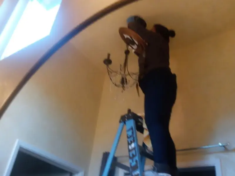 Electrician installing a chandelier in a Rye residence